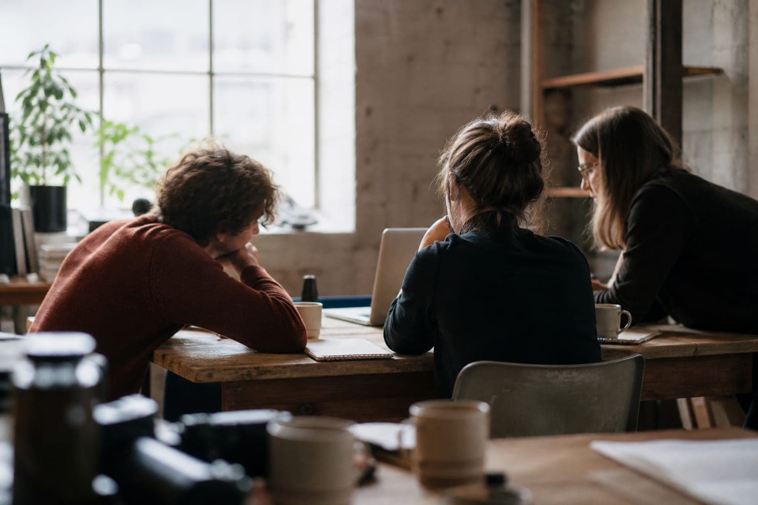 A small studio team setting up a workspace together on one laptop